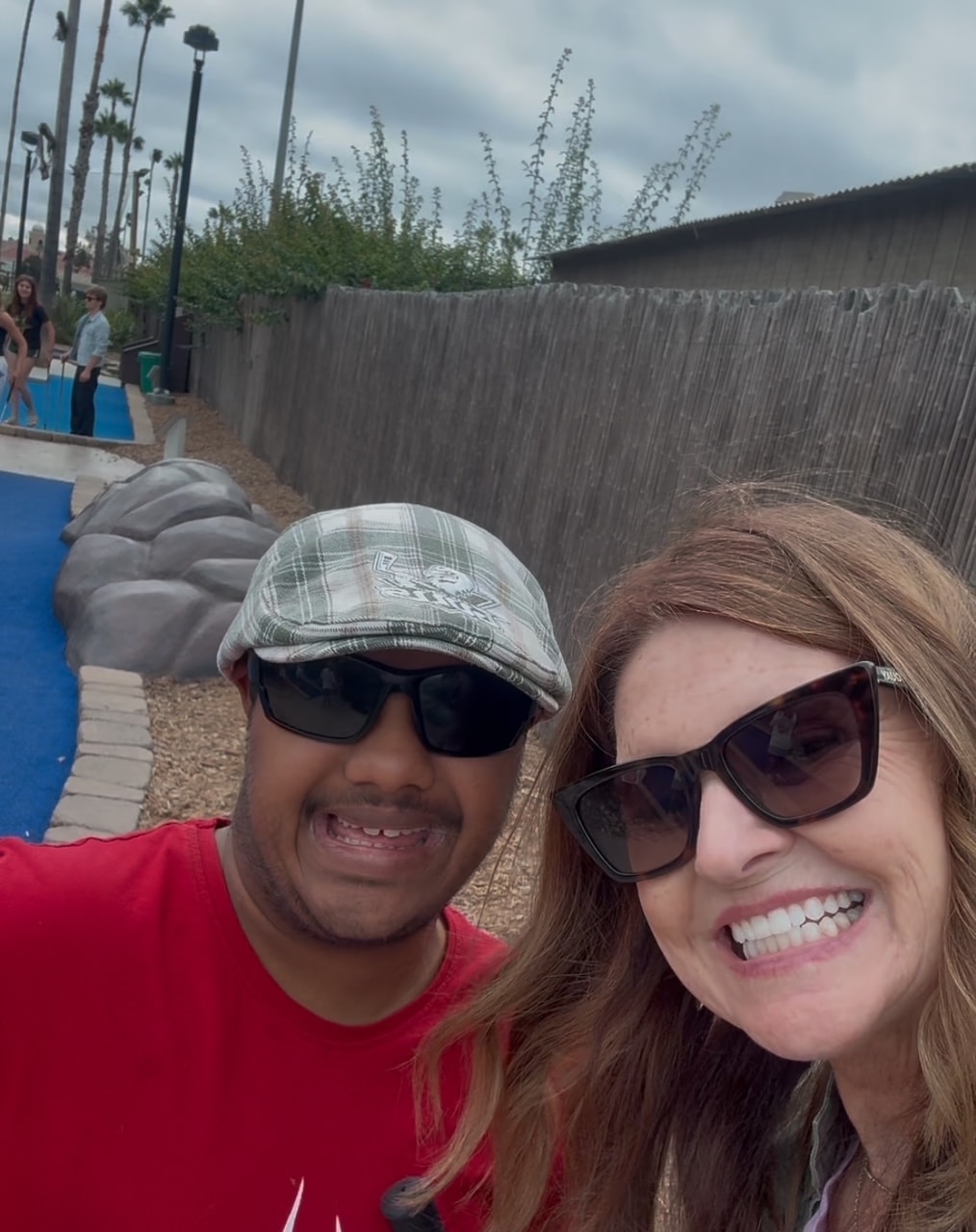 Two friends smiling together at mini golf outing